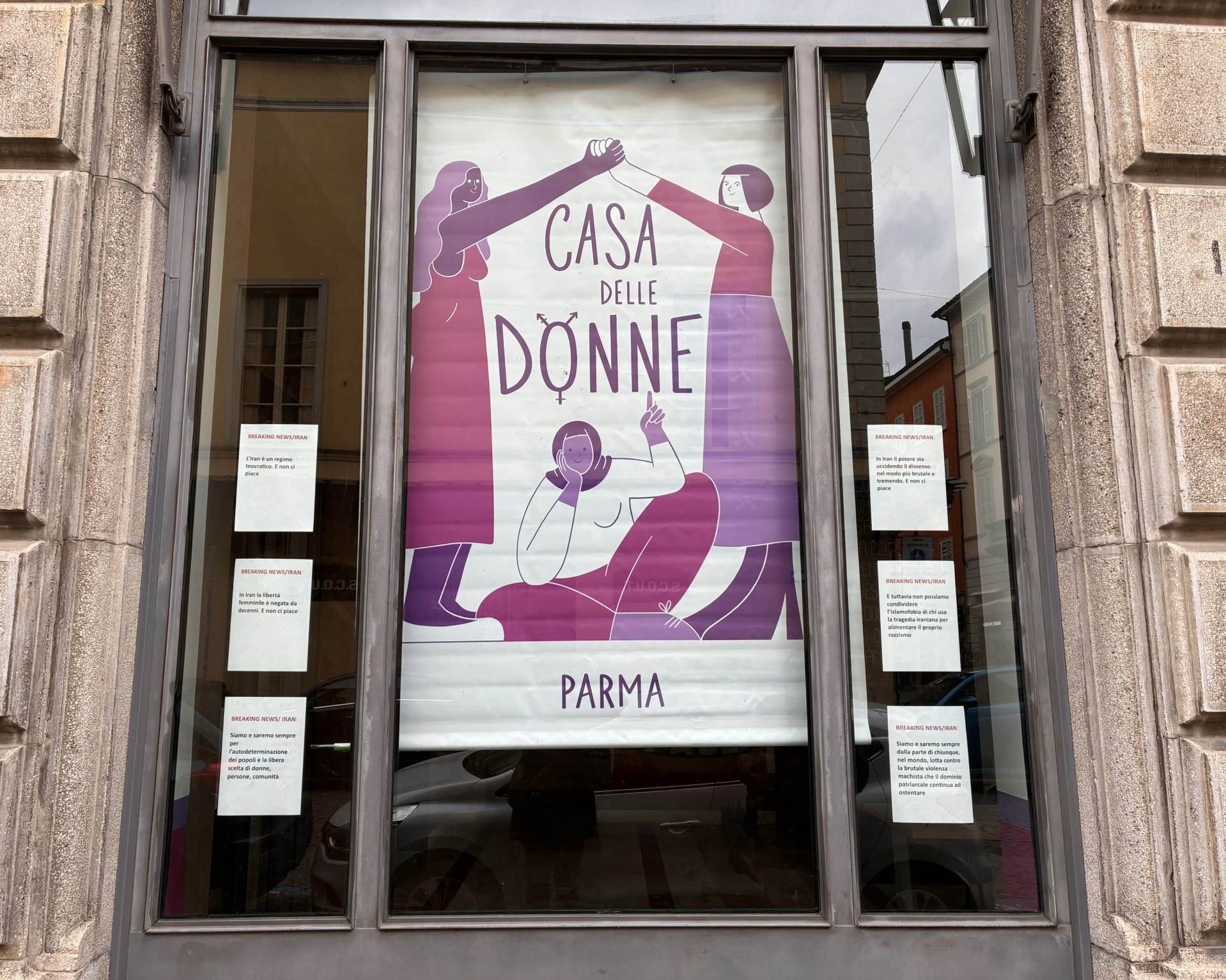 Immagine della vetrina della sede della Casa delle Donne di Parma con il banner del logo.