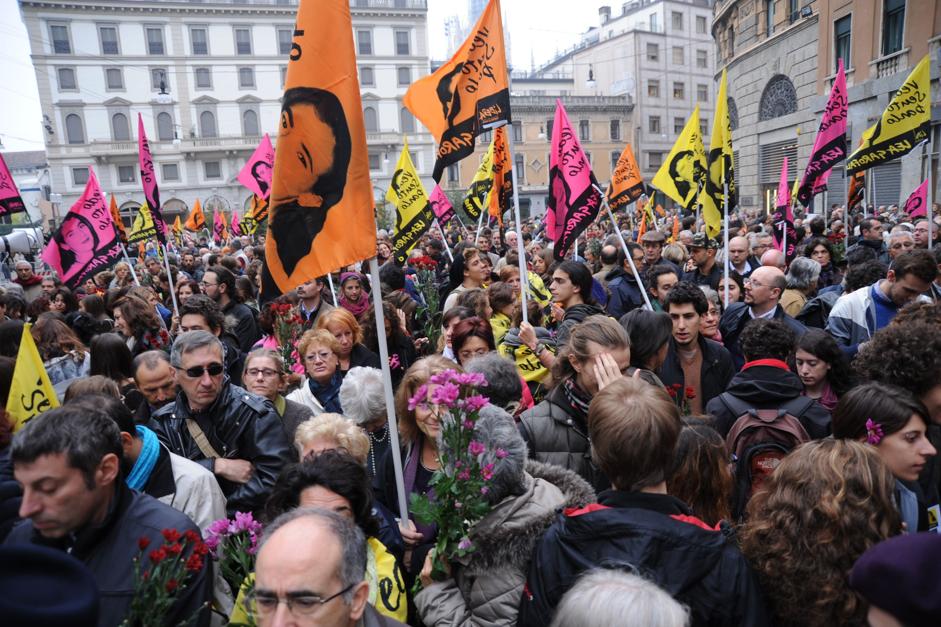 Foto delle bandiere gialle, arancioni e fucsia di Libera con il volto di Lea Garofalo durante il funerale a Milano in Piazza Cesare Beccaria
